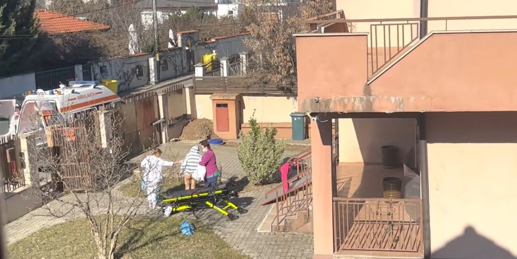 în curtea centrului, unul dintre reidenți este dezbrăcat complet de la brâu în jos. Două îngrijitoare  îl duc spre ambulanța din fața porții.